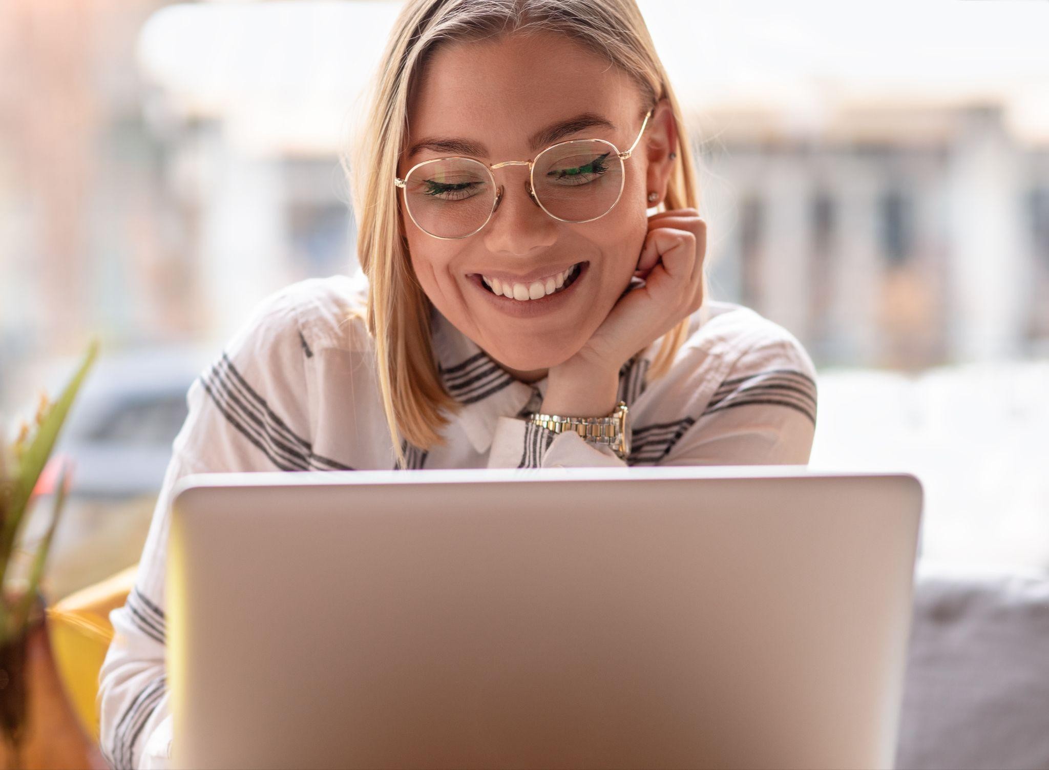smiling woman looking at her laptop screen